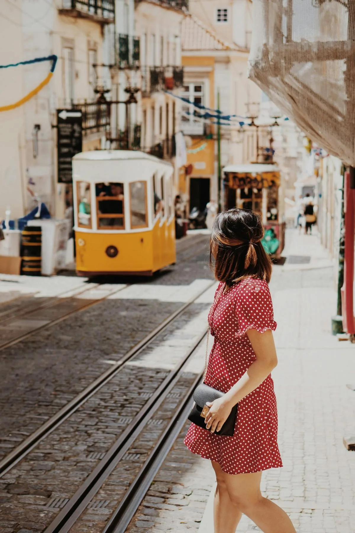 A woman in a red dress crossing the tram lines
