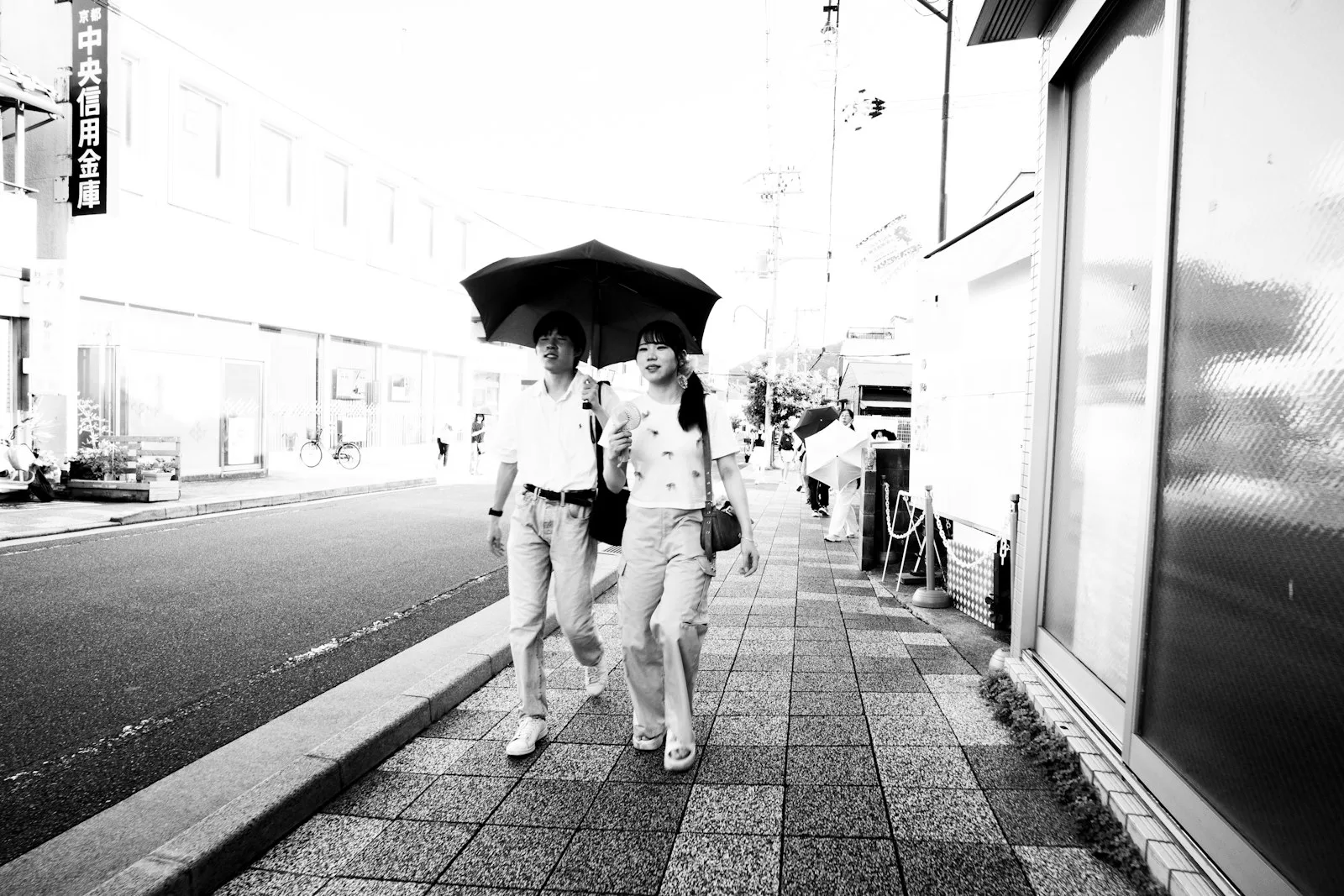 Two people sharing an umbrella, in black and white