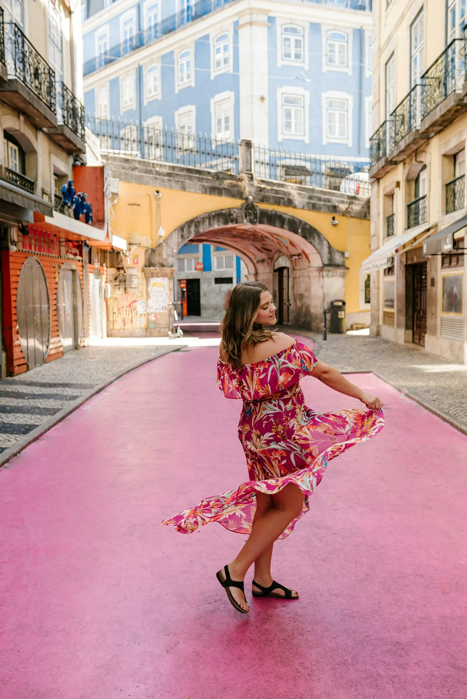 A woman in a red dress walking a pink street