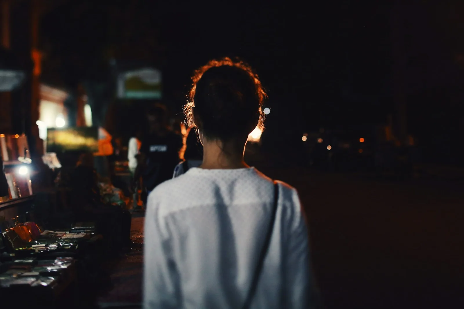 A woman seen from behind, framed by night lights